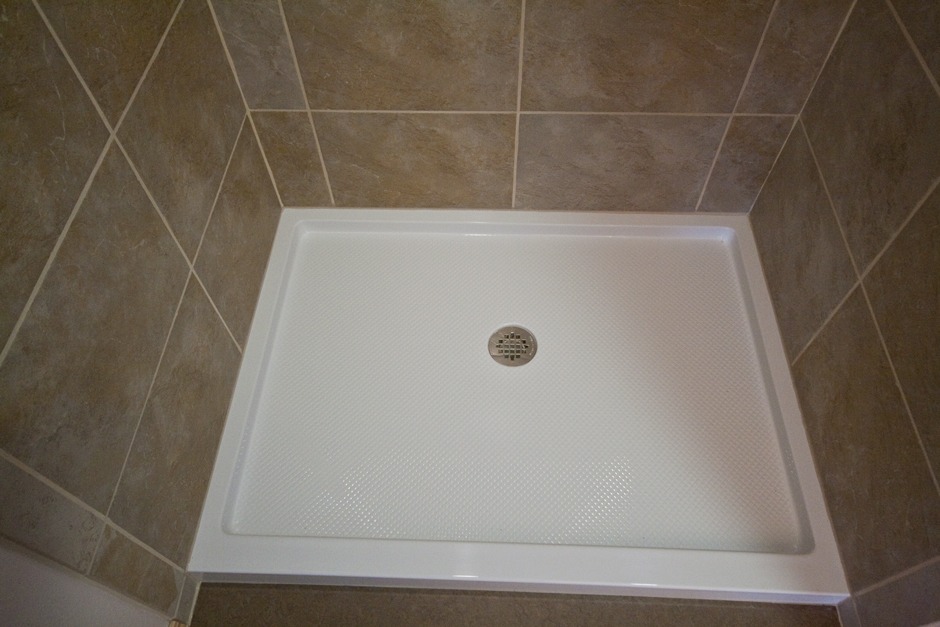 white acrylic shower pan with sandy beige tile surround