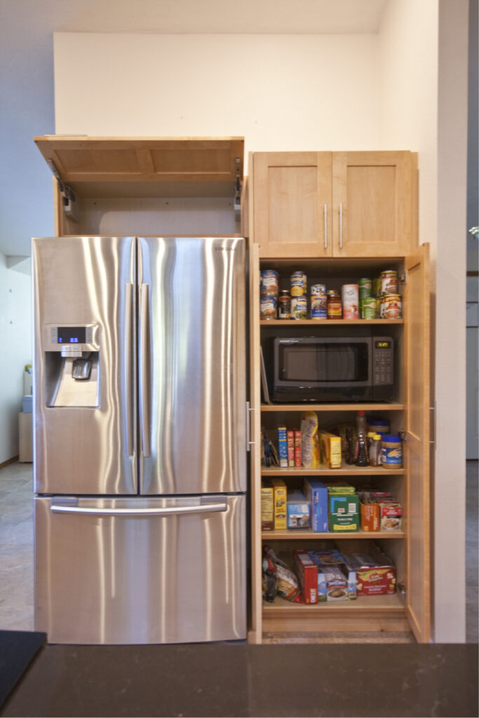 Lift-up cabinet door over fridge and microwave hidden in tall cabinet.  