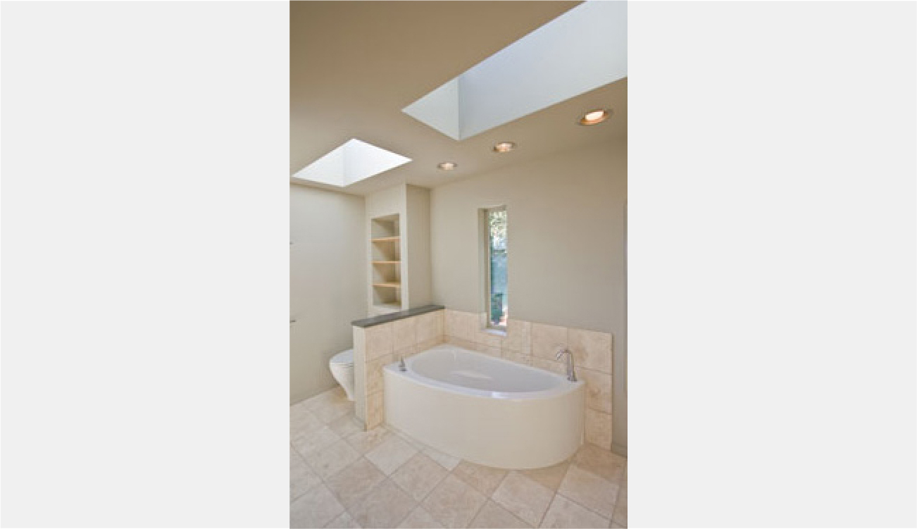 Curved soaker tub and recessed shelves behind toilet
