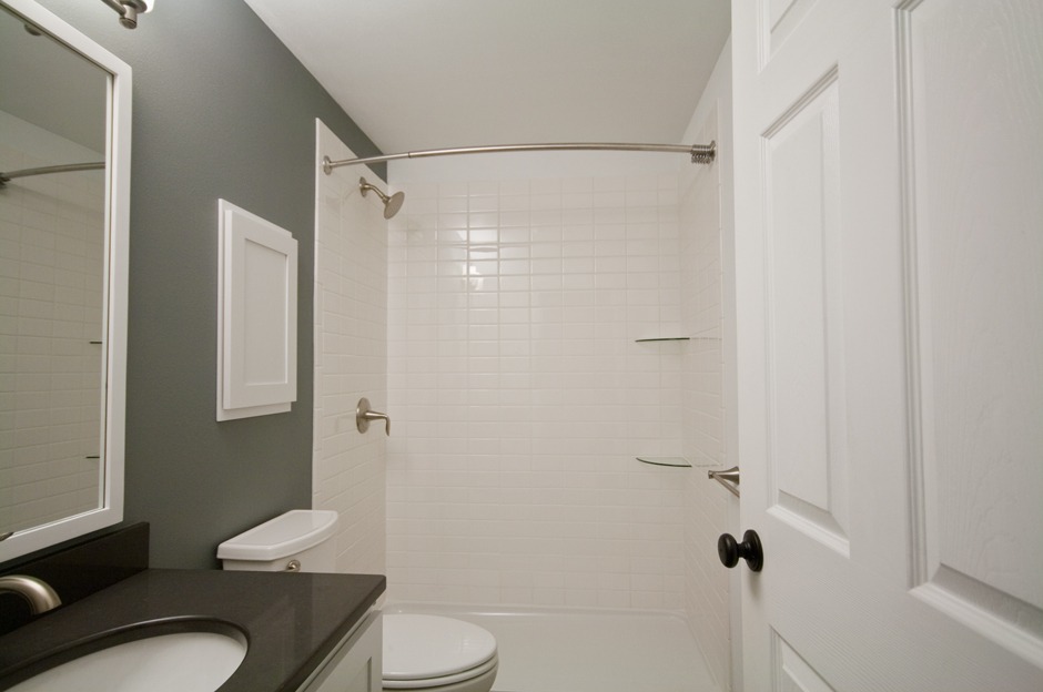 White subway tile shower surround with rounded glass corner shelves