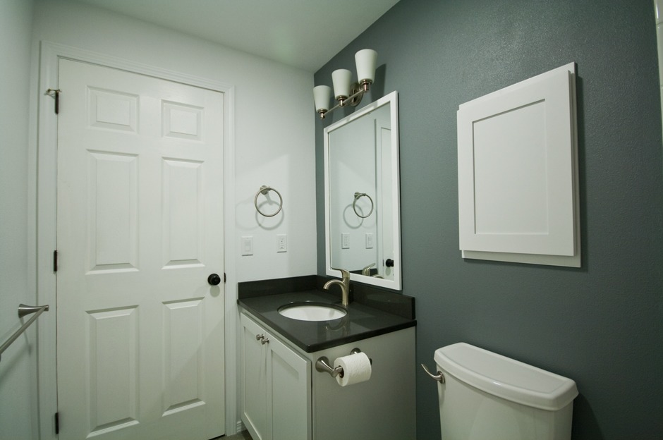 Newly re-done bathroom with slate blue accent wall, 6-panel white door
