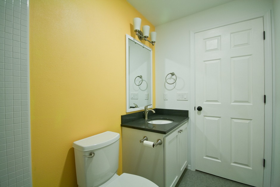 Bathroom remodel with white custom mirror frame, yellow accent wall