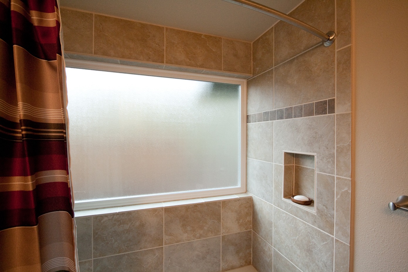 Large obscure-glass window in shower wall, plus tiled recessed soap niche