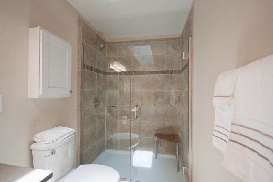 Shower remodel with low-flush toilet & white medicine cabinet.