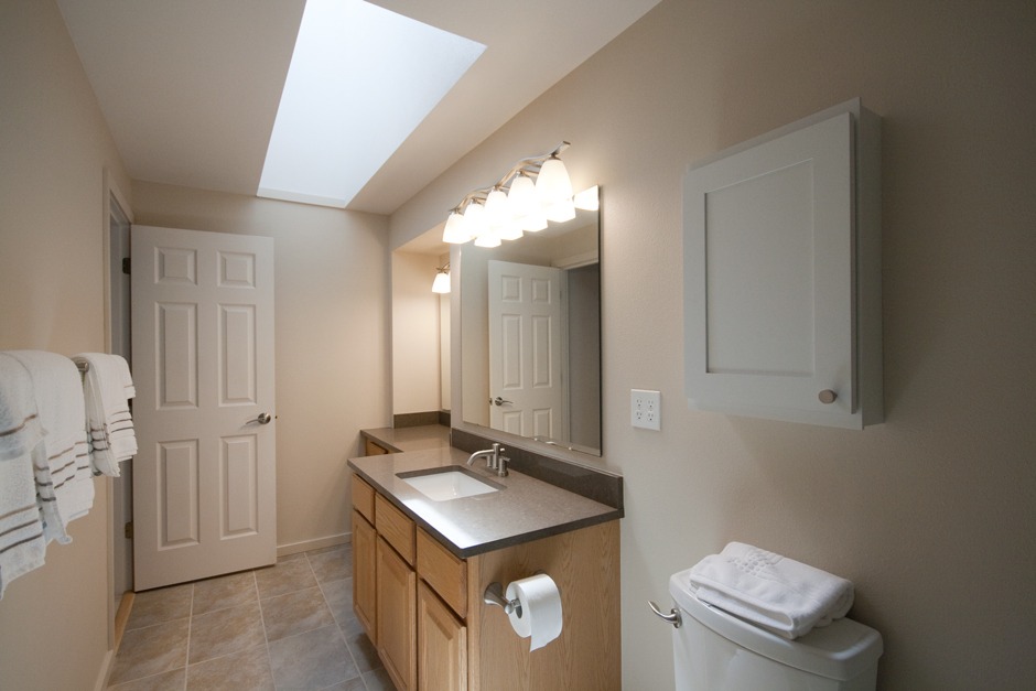 Bathroom remodel with skylight, white 6-panel door, quartz counters.