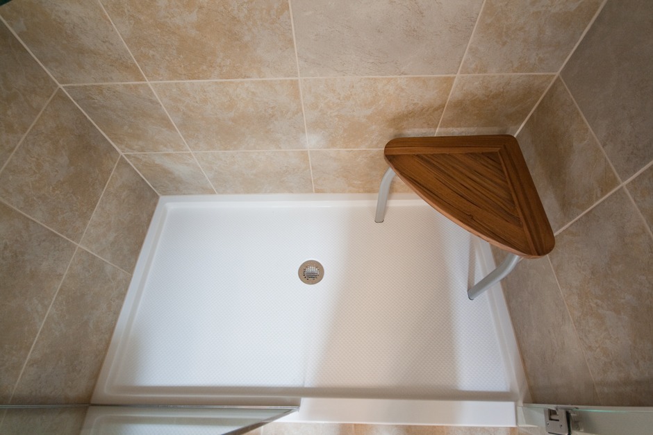 Tiled shower with acrylic pan, teak corner shower seat.