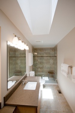 Brown tone bath remodel with dramatic skylight.