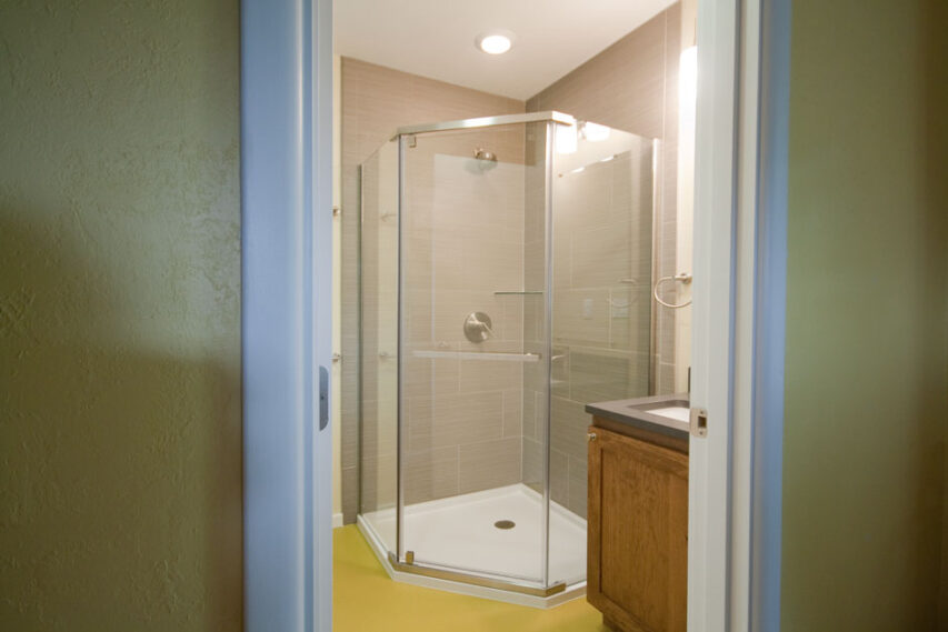 Luxury neo-angle shower with chartreuse sheet flooring.