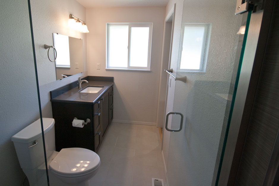 view from newly remodeled shower of toilet, vanity, slider window