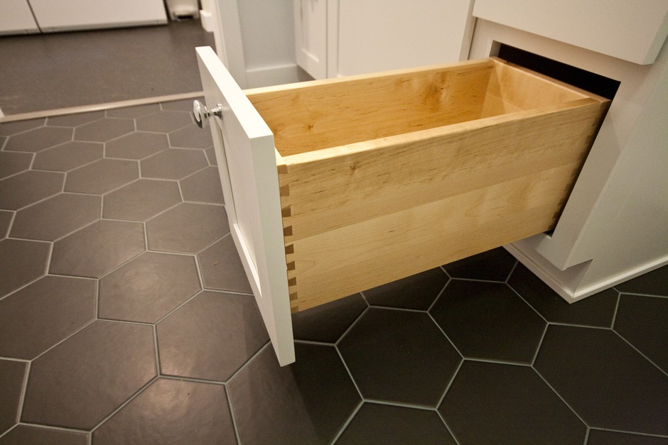 beautiful dovetail vanity drawer over black hex tile in bathroom