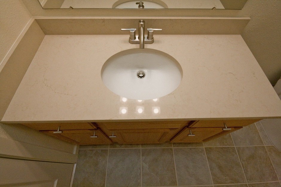 Quartz bathroom vanity counter with under-mount sink and oak cabinet.