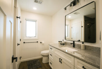 Bathroom Builder bathroom pictures: Bathroom remodel with gray vanity counter, black-framed mirror and brown vinyl plank flooring