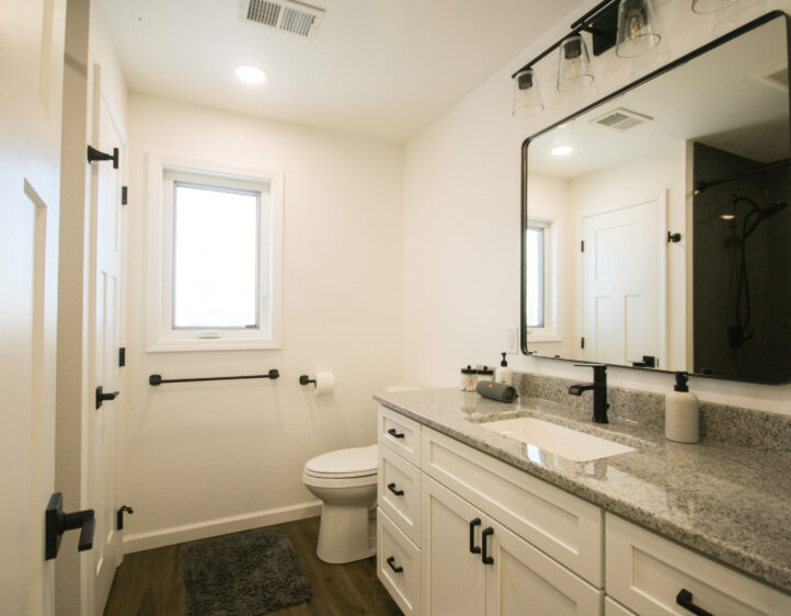 Bathroom Builder bathroom pictures: Bathroom remodel with gray vanity counter, black-framed mirror and brown vinyl plank flooring
